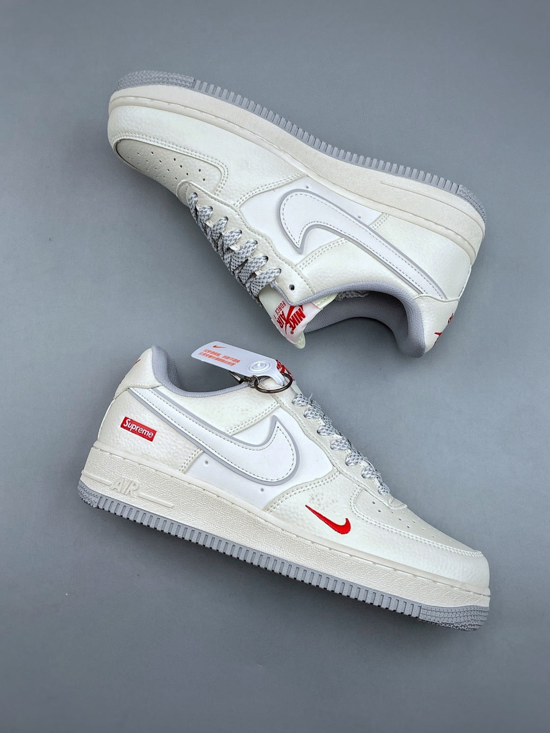 White low top sneakers with grey soles and red accents, pair view